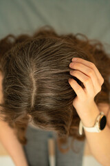 Naklejka premium Close-up top view of mature woman grasping her head, showing natural gray hair. Concept of aging, beauty, hair care, body awareness, and embracing natural changes with confidence.