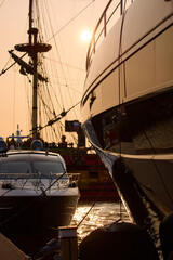 A yacht club at sunset, yachts and sailboats are moored to the berths, huge fenders hang on mega...