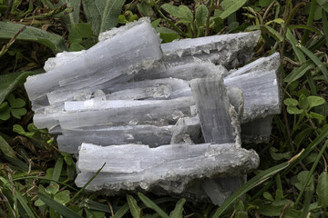 cyanite mineral featuring elongated, fibrous blue-gray crystals placed on a natural grass background. Ideal for geology, science education, mineral collections, or nature-themed visual content