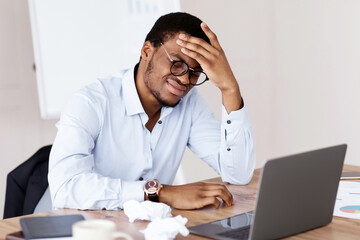 Desperate african american manager or ceo in formal shirt suffering from financial crisis, sitting...