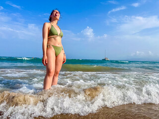 A woman in a green bikini stands in the ocean