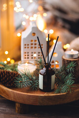 Creating cozy holiday Christmas home atmosphere. Liquid reed diffuser with sticks with xmas scent: vanilla, gingerbread cookies, pine, sweet pie, cinnamon, anise. Aromatherapy, wellness, relaxation