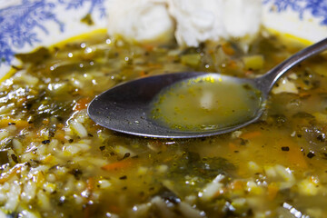 A spoon inside a porcelain plate full of rice soup