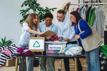 Group of volunteers, young women and man, sorting clothes in charitable foundation for charity donation, recycling. Concept of textile pollution, conscious consumption. Ecology, sustainable lifestyle