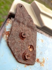 The refrigerator door hinges are worn and rusty