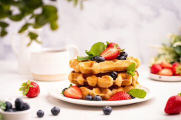 Tasty Belgian waffles with fresh berries, cheese and powdered sugar on white table, close up. High quality photo