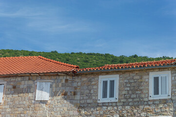 Old stone house with small windows, tiled roof and blue sky on the Adriatic coast in Montenegro Petrovac