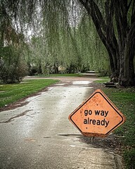 A serene curved path is marked by an intriguing sign 'go way already', capturing a moment of quiet reflection amidst lush surroundings and inviting the viewer's curiosity.