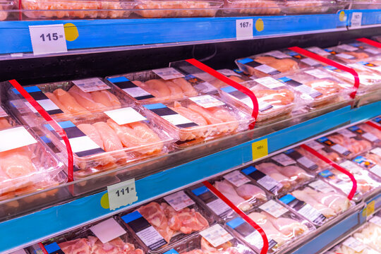 Package of organic chicken meat neatly arranged on supermarket refrigerator shelves for sale. Display with fresh poultry in grocery store in Thailand. Food retail