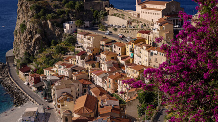 Aerial view of Scilla, Calabria, Italy, featuring colorful houses, purple flowers, and the...