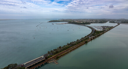 Aerial view of the Tamaki Drive causeway road and railway connecting land, with a marina full of boats in the sea, Auckland, New Zealand