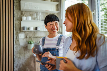 two diverse female friends use mobile phone and have fun at home