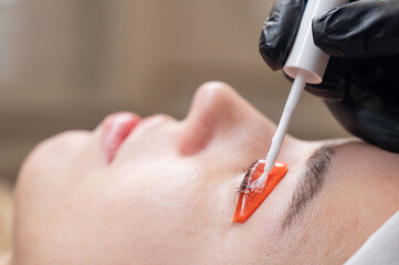 Caucasian woman undergoing eyelash lamination procedure. 