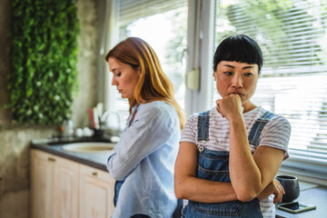 Two multicultural diverse women stand in the kitchen and arguing