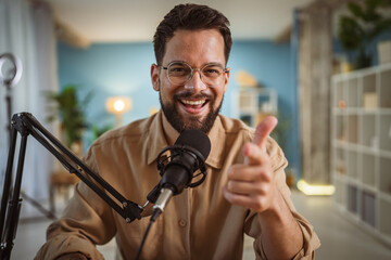 Adult man with eyeglasses and headphones smile while record a podcast