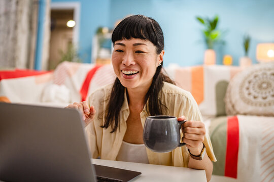 Japanese woman freelancer work from home use laptop in living room