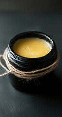 Pot of  yellow,  smooth balm.  Dark background