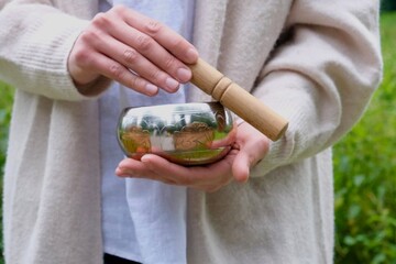 Musical bowl in hands. Girl with a musical bowl. Concept: meditation, relaxation, music therapy. 