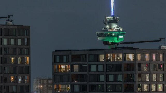 Rotterdam night cityscape timelapse with Euromast observation tower and glowing windows in high-rise buildings. Waterfront features illuminated modern skyscrapers and a scenic harbor view