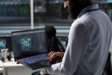 Data center engineer uses AI visualization tool on laptop to optimize resource allocation. Server hub IT expert uses artificial intelligence analysis on notebook to do maintenance