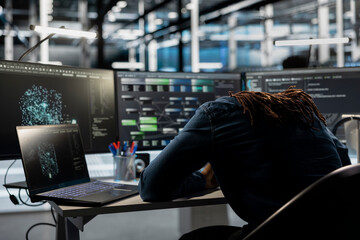 Exhausted server farm engineer falls asleep while looking at data analysis graph to reduce...