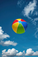Colorful inflatable beach ball floating in bright blue sky with white fluffy clouds