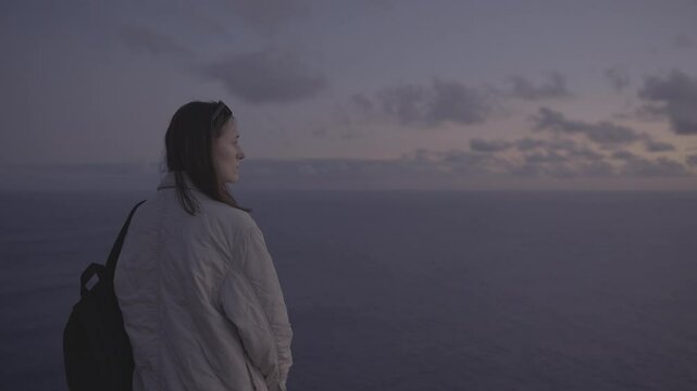 Woman admiring pink and purple Madeira sunset over Atlantic Ocean (SLOG3)