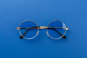 Blue sunglasses on color background, top view