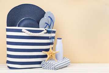 Blue beach bag with summer accessories on wooden table