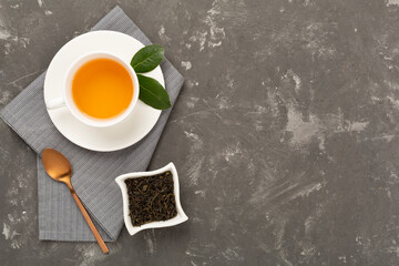 Cup of tea with dry and fresh leaves on concrete background, top view