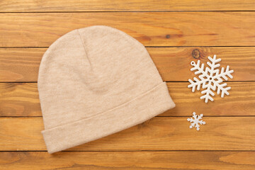 Stylish beanie hat on wooden background, top view