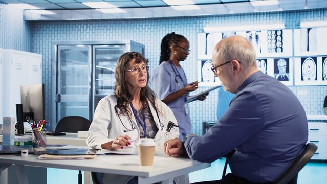 Female doctor in a clinic evaluates a man cognitive function and reflex, using a pen light to test pupil response and focus after a head trauma. Healthcare provider. Camera A.