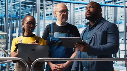 Manager overseeing smart factory, giving instructions to engineers testing automated systems....