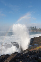 A beautiful water spout through the rocks with a rainbow through the spray