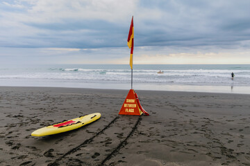 Swimmers and surfers enjoy the ocean safely between the red and yellow surf lifesaving flags on a...