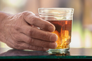 Man in the shadows holding a glass of alcohol