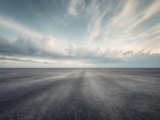 Fototapeta premium A vast, empty asphalt road stretching to the horizon under a dramatic, cloudy sky, creating a sense of openness and journey.
