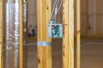 Construction workers install an electrical box in newly framed room while building house.