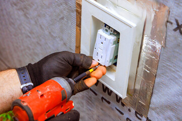 An electrician works on installing an electrical outlet in home, ensuring safe efficient wiring.
