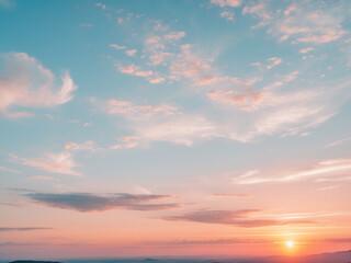 Obraz premium A panoramic landscape photograph capturing a beautiful sunrise or sunset sky with soft pastel clouds in hues of blue, pink, and orange.