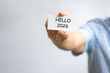 Man holding a white card with Hello 2026. Isolated on white background.
