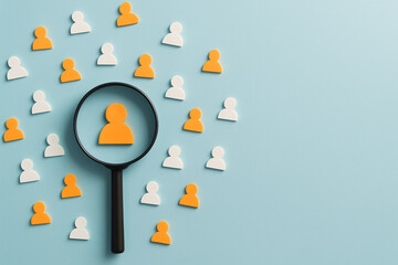 Magnifying glass focusing on user icon among group on blue background