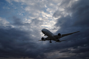 曇り空の早朝、着陸態勢で上空を飛んでいく飛行機