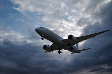 曇り空の早朝、着陸態勢で上空を飛んでいく飛行機