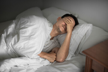Sleepless man lying in bed feeling tired exhausted stressed waking up unmotivated 