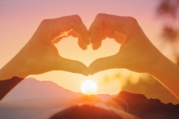 Hand making heart shape on beautiful sunset background. kindness love nature concept	