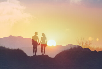 silhouette of a couple walking in the mountains talking  holding hands enjoying nature together 