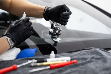 Windshield crack repair using resin injection. Technician using windshield injector tool to fix...