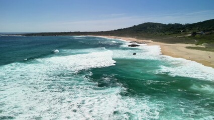 Take a breathtaking aerial view of a stunning coastal beach featuring waves and clear blue water