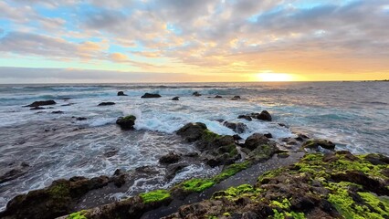 A breathtaking ocean sunset gracefully illuminating the rocky coastline and shoreline